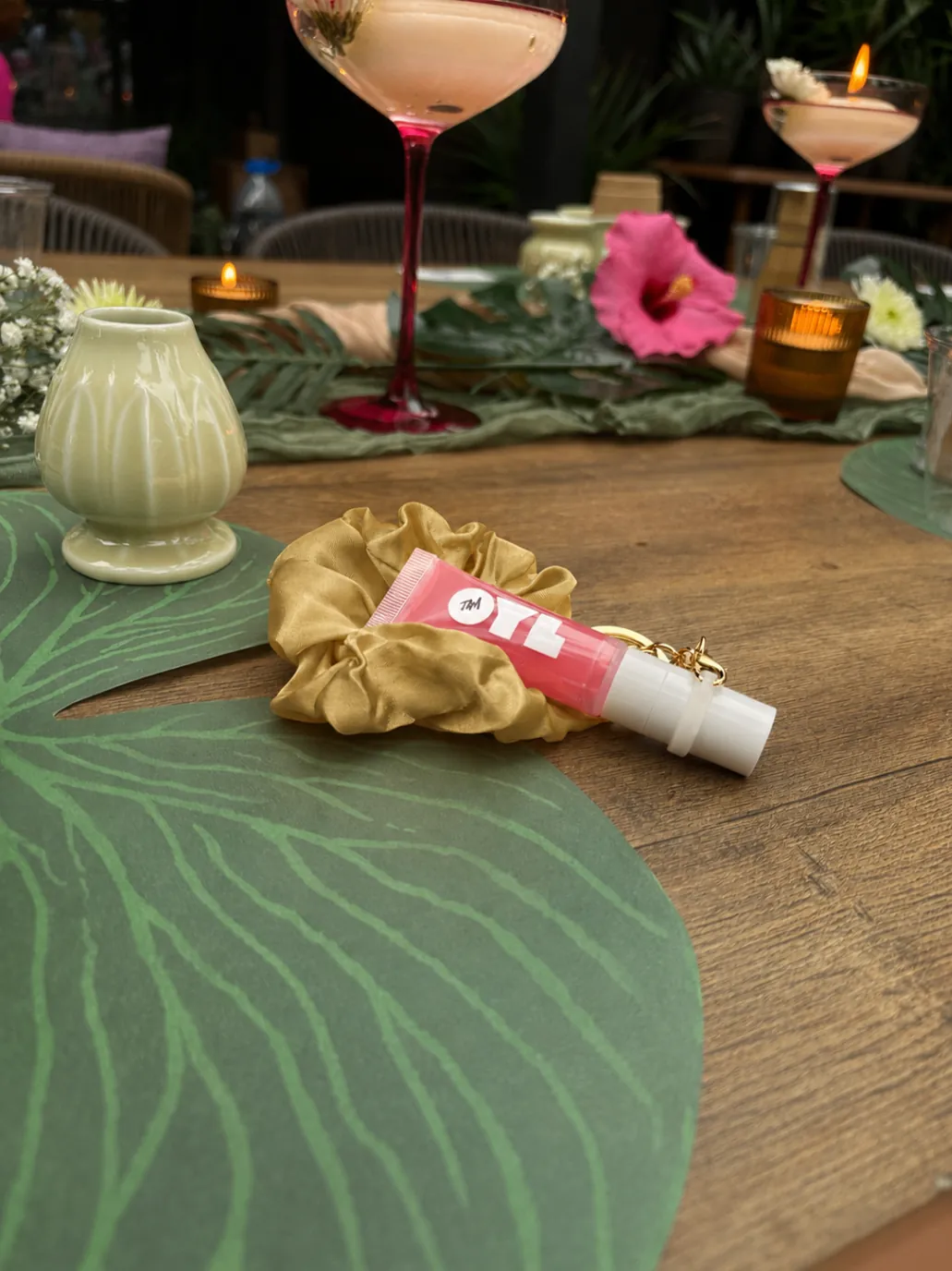 OylJam™ Lip Oil Top Coat in Guava styled tableside with the gold keychain charm and scrunchie.