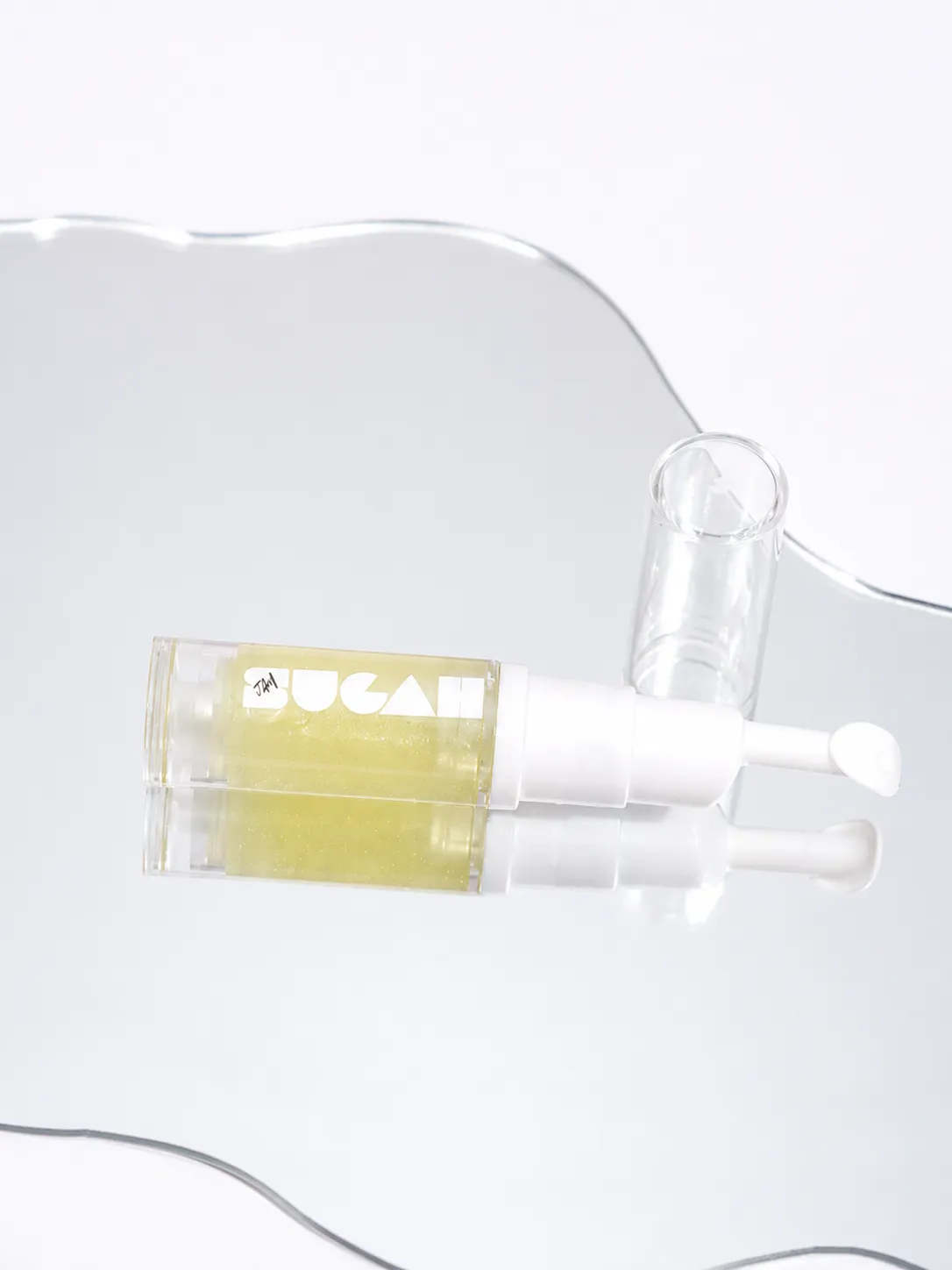 SugahJam™ Jelly Lip Mask in Coconut Key Lime resting on a wavy mirror, golden jelly catching the light.