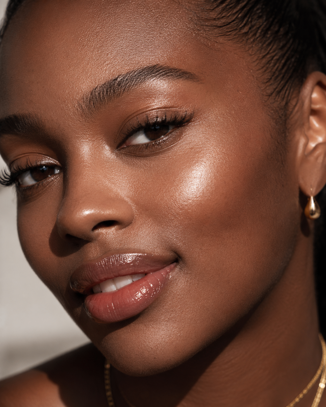 Close editorial portrait with glossy lips and luminous skin detail.