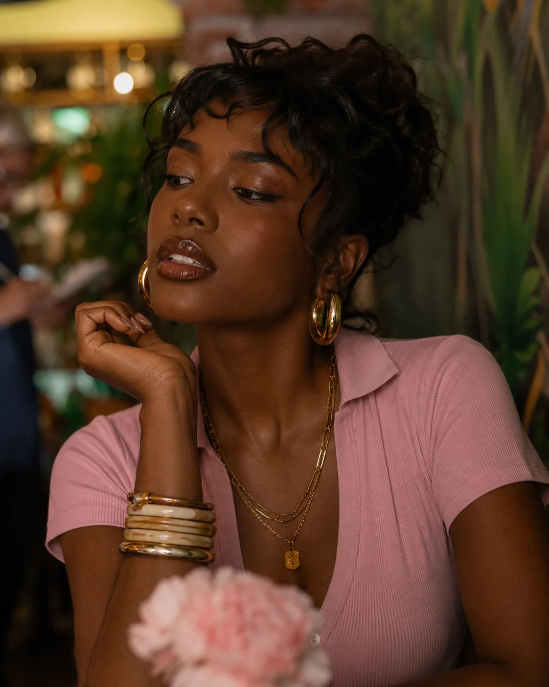Editorial beauty portrait of a woman with glossy lips in a soft pink top.